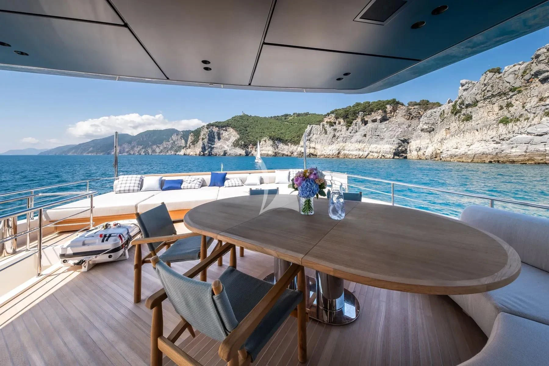 a table and chairs on a deck overlooking a body of water aboard AKIRA Yacht for Sale