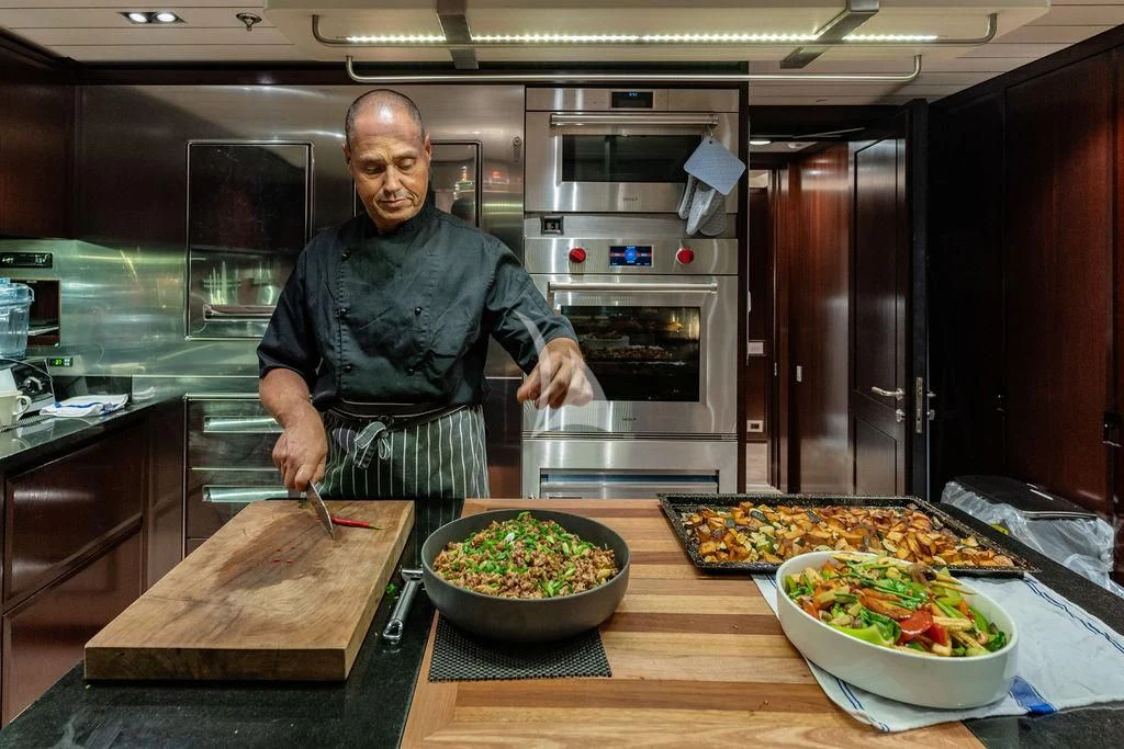 a person in a kitchen preparing food aboard GALILEO Yacht for Sale