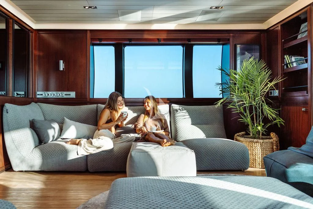 a couple of women sitting on a couch in a living room aboard GALILEO Yacht for Sale