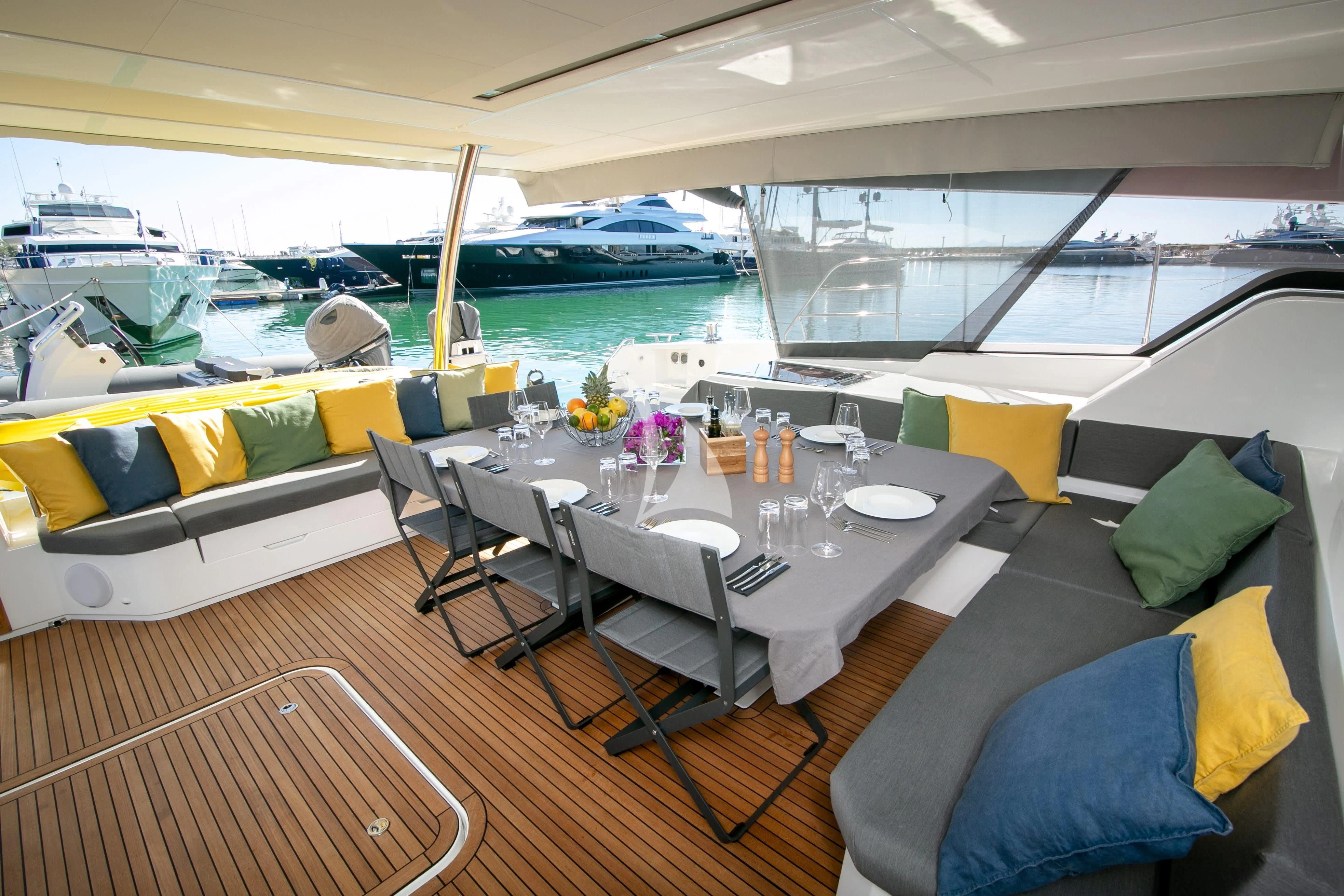 a room with a table chairs and a large window with a view of the water aboard ALOIA Yacht for Charter