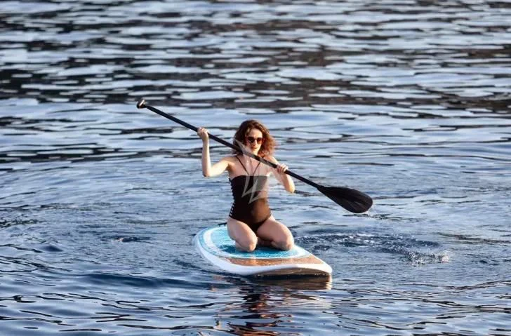 a woman in a bikini paddle boarding aboard CHANTELLA Yacht for Sale