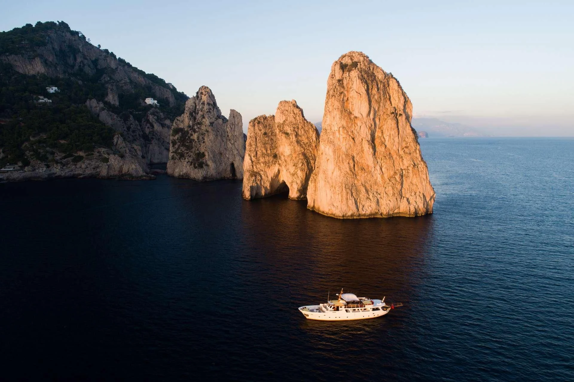 a boat in the water by a large rock formation aboard ENTRANCER Yacht for Sale
