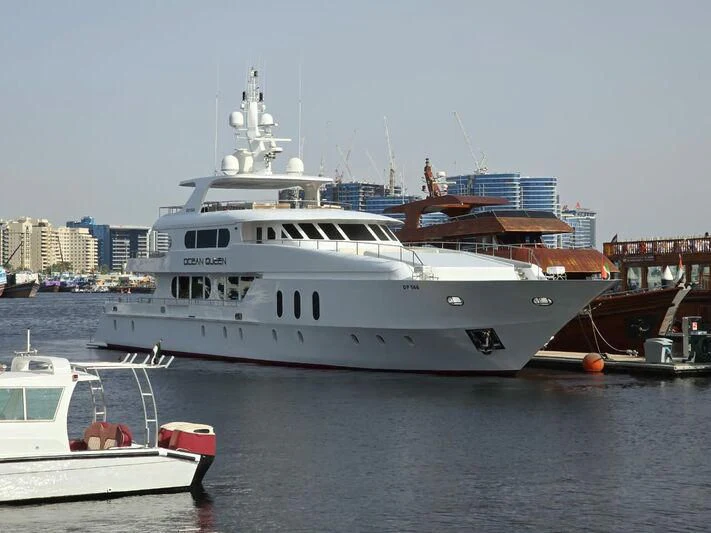 a large white boat sits next to a smaller boat aboard OCEAN QUEEN Yacht for Sale