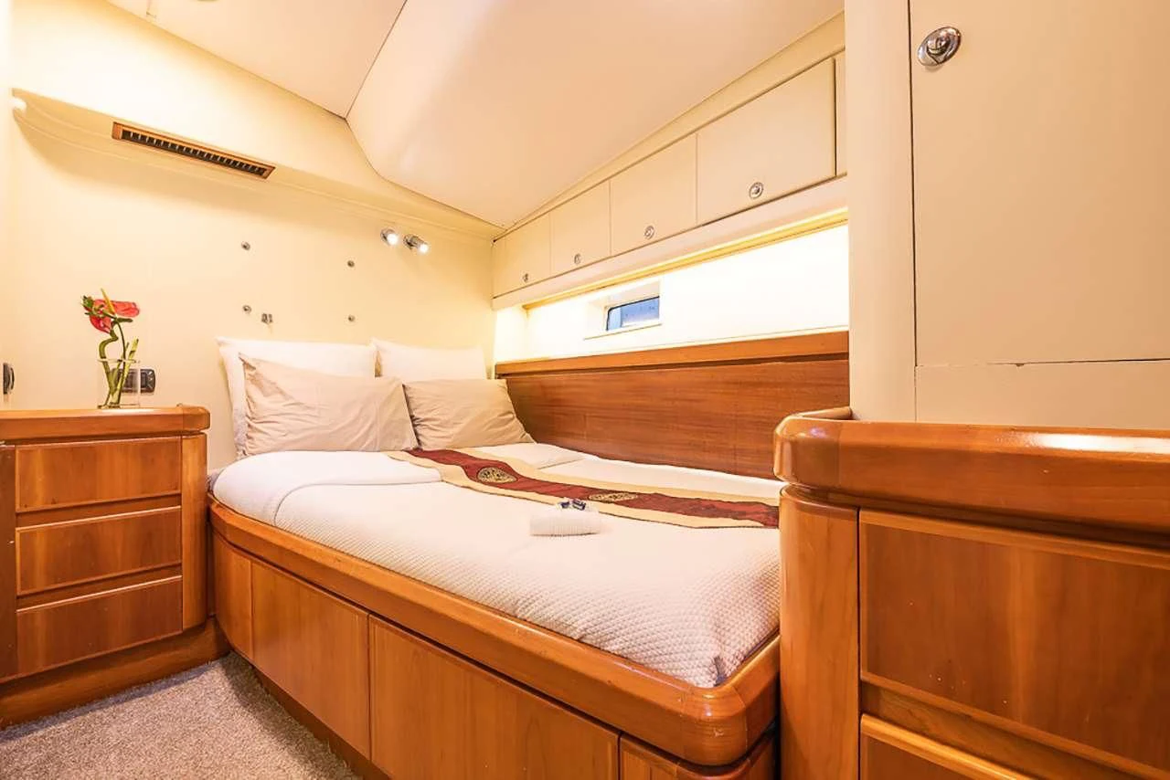 a bed with a white sheet and a wooden cabinet aboard OCEAN PHOENIX Yacht for Sale