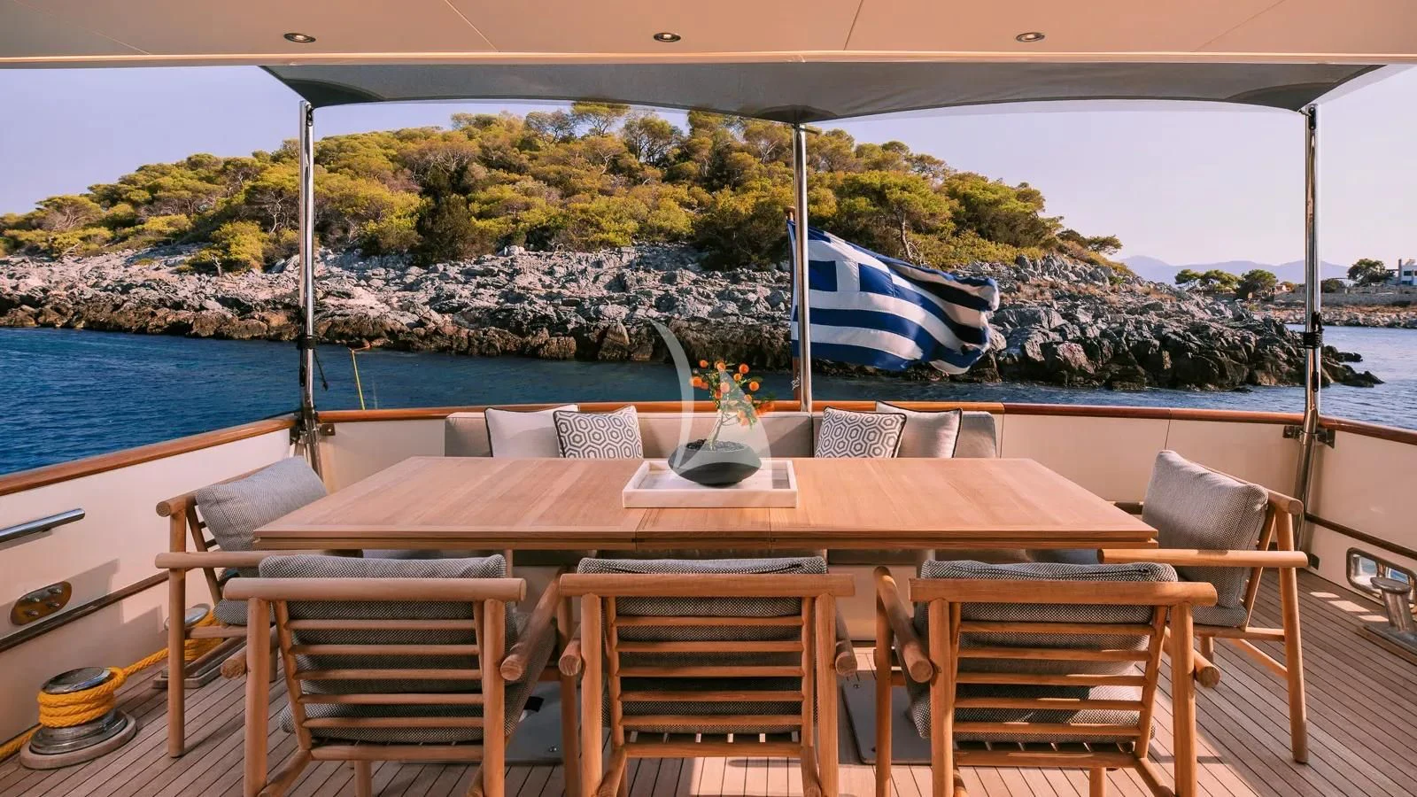 a table and chairs on a balcony overlooking a body of water aboard XIPHIAS Yacht for Charter