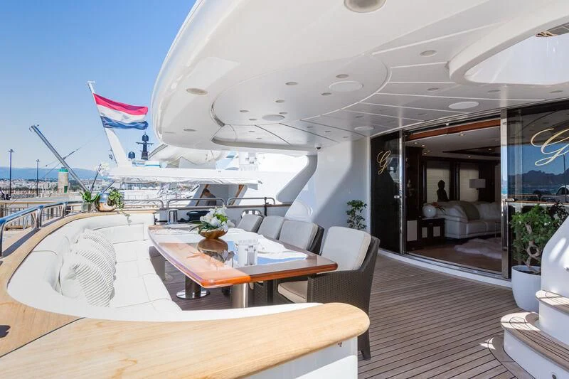a room with a table chairs and a large boat in the water aboard GIORGIA I Yacht for Sale