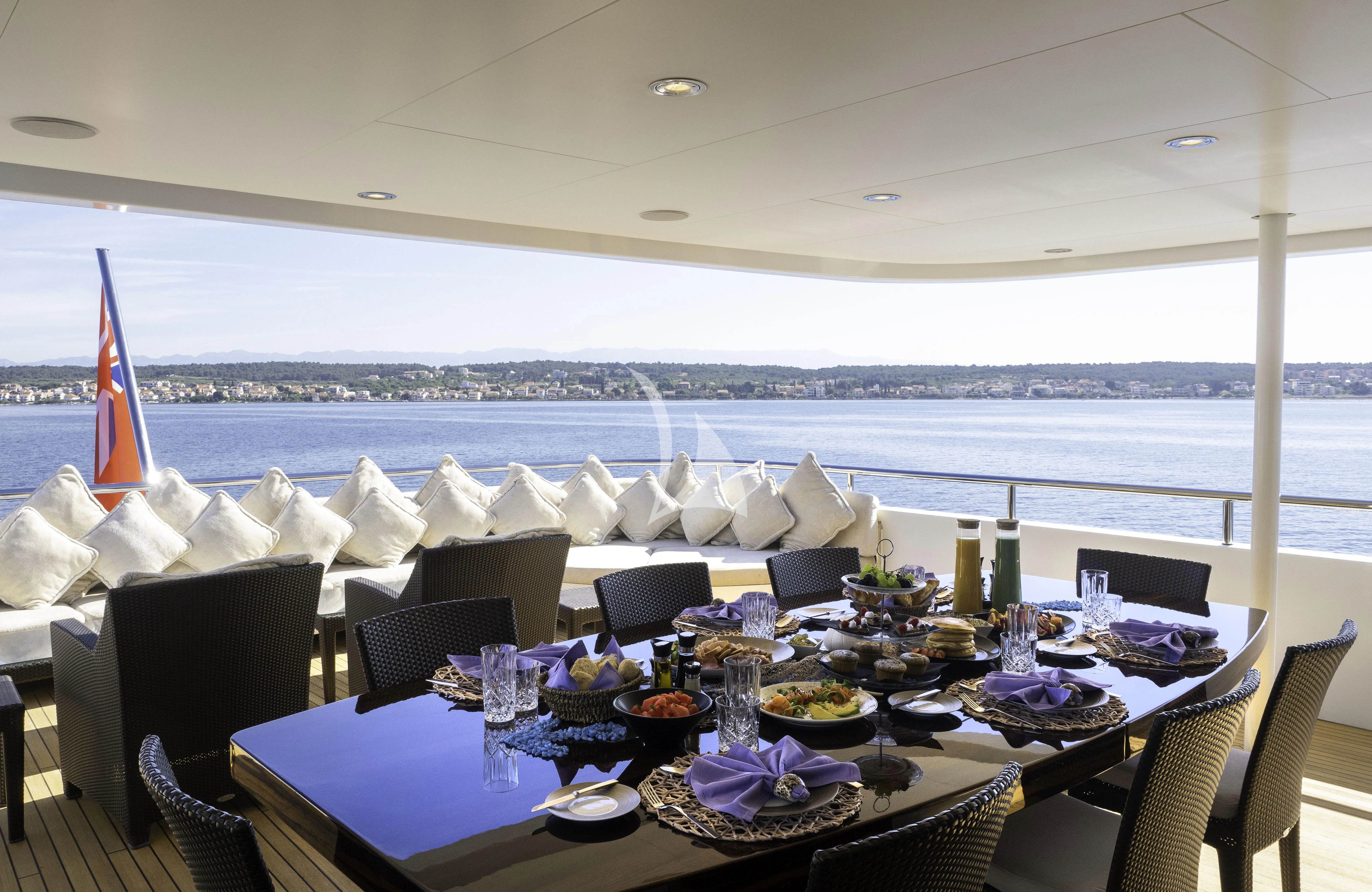 a table set for a meal on a balcony overlooking a large body of water aboard MY LITTLE VIOLET Yacht for Sale