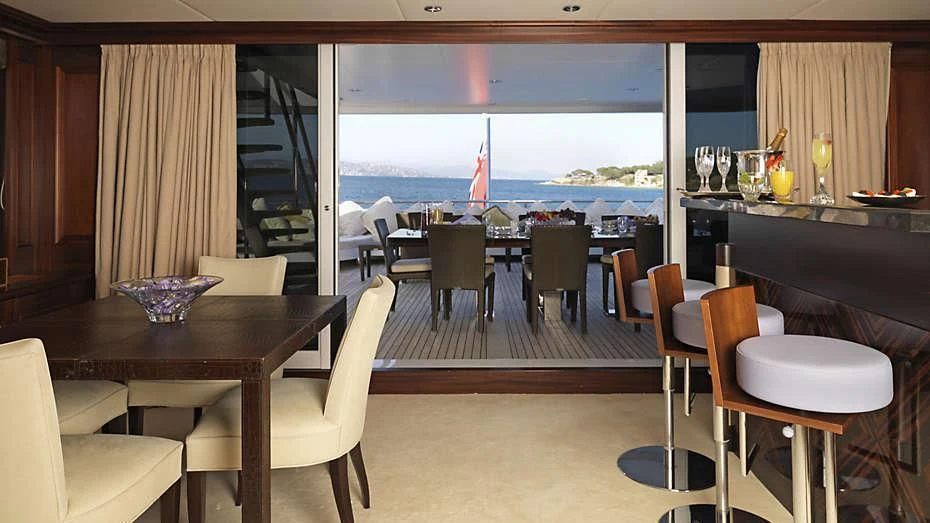 a room with a table chairs and a window with a view of the water aboard MY LITTLE VIOLET Yacht for Sale