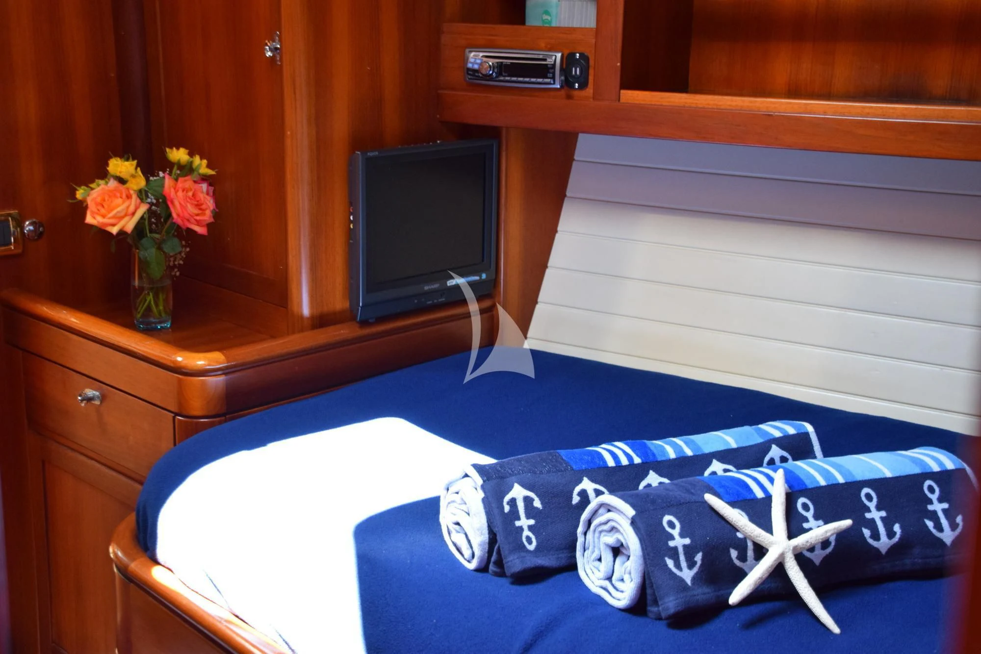 a bed with a blue and white pillow and a vase with flowers on it aboard LUNA DANNS Yacht for Sale