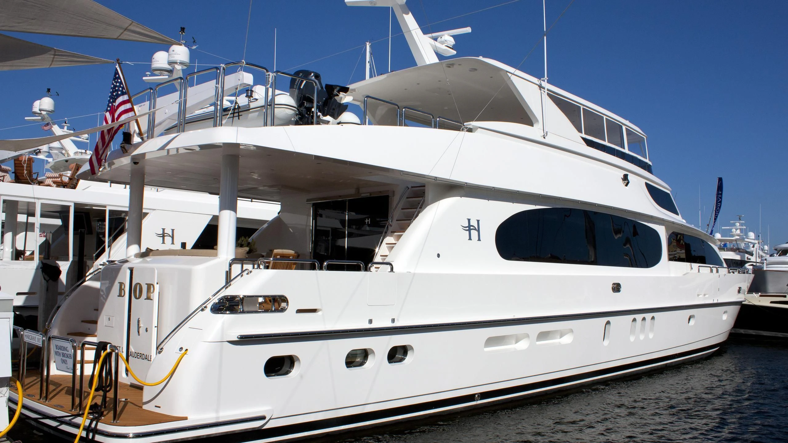 a white yacht with a flag on the front aboard EBITDA Yacht for Sale