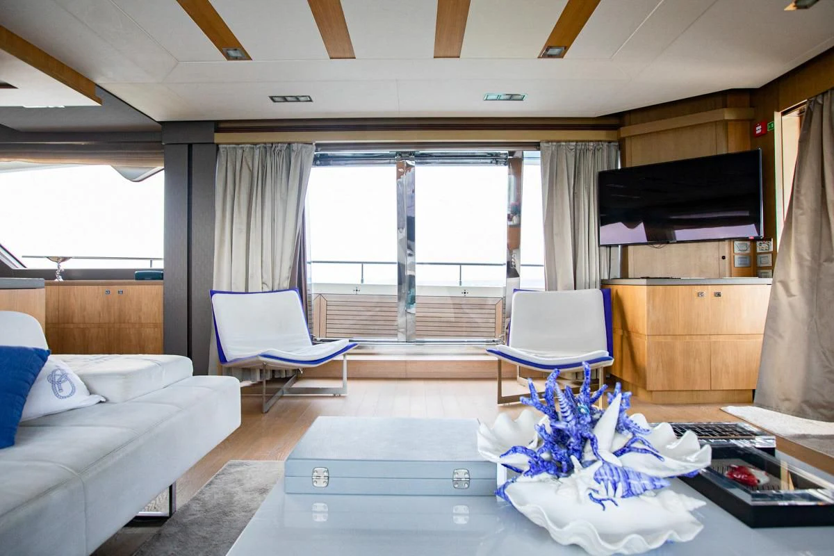 a living room with a blue chair and a large window aboard NIKO III Yacht for Charter