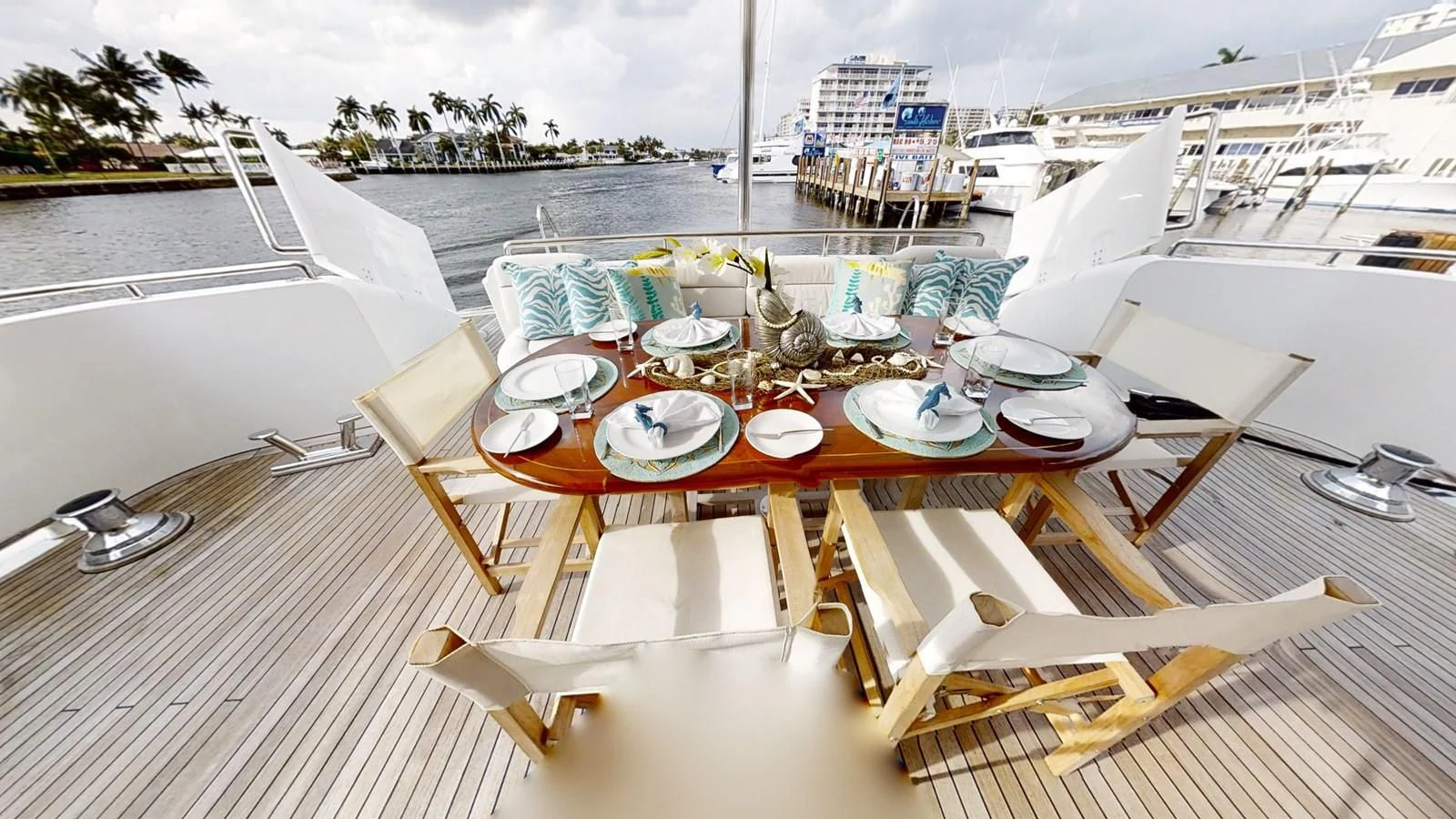 a table set with plates and chairs on a deck overlooking a large ship aboard ENTOURAGE Yacht for Sale