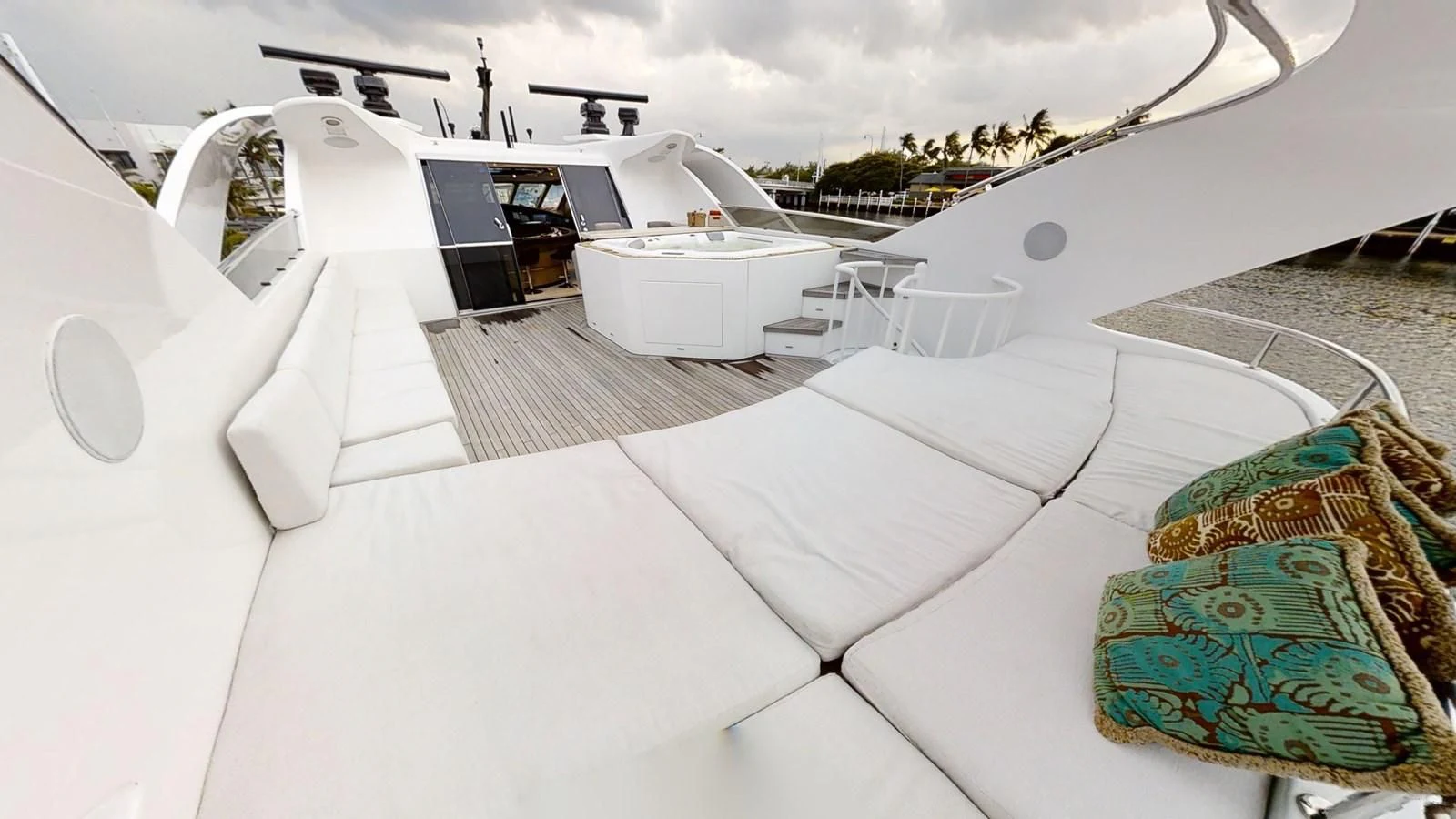 a white lounge chair on a white floor with a black and white patterned pillow and a green pillow aboard ENTOURAGE Yacht for Sale
