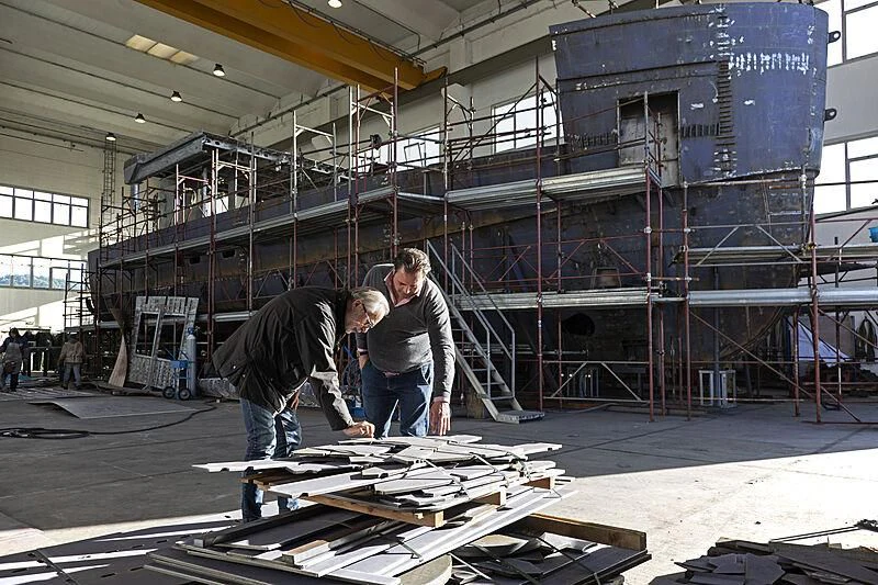 a few men working on a piece of wood aboard REALE PACIFICO 32#1 Yacht for Sale