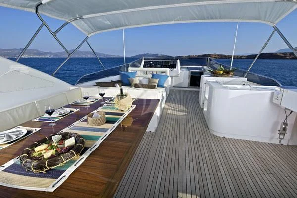a deck with a view of the ocean and a boat aboard HELIOS Yacht for Charter