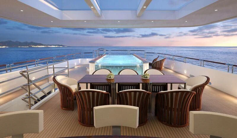 a table and chairs on a deck overlooking a large body of water aboard INGOT Yacht for Sale