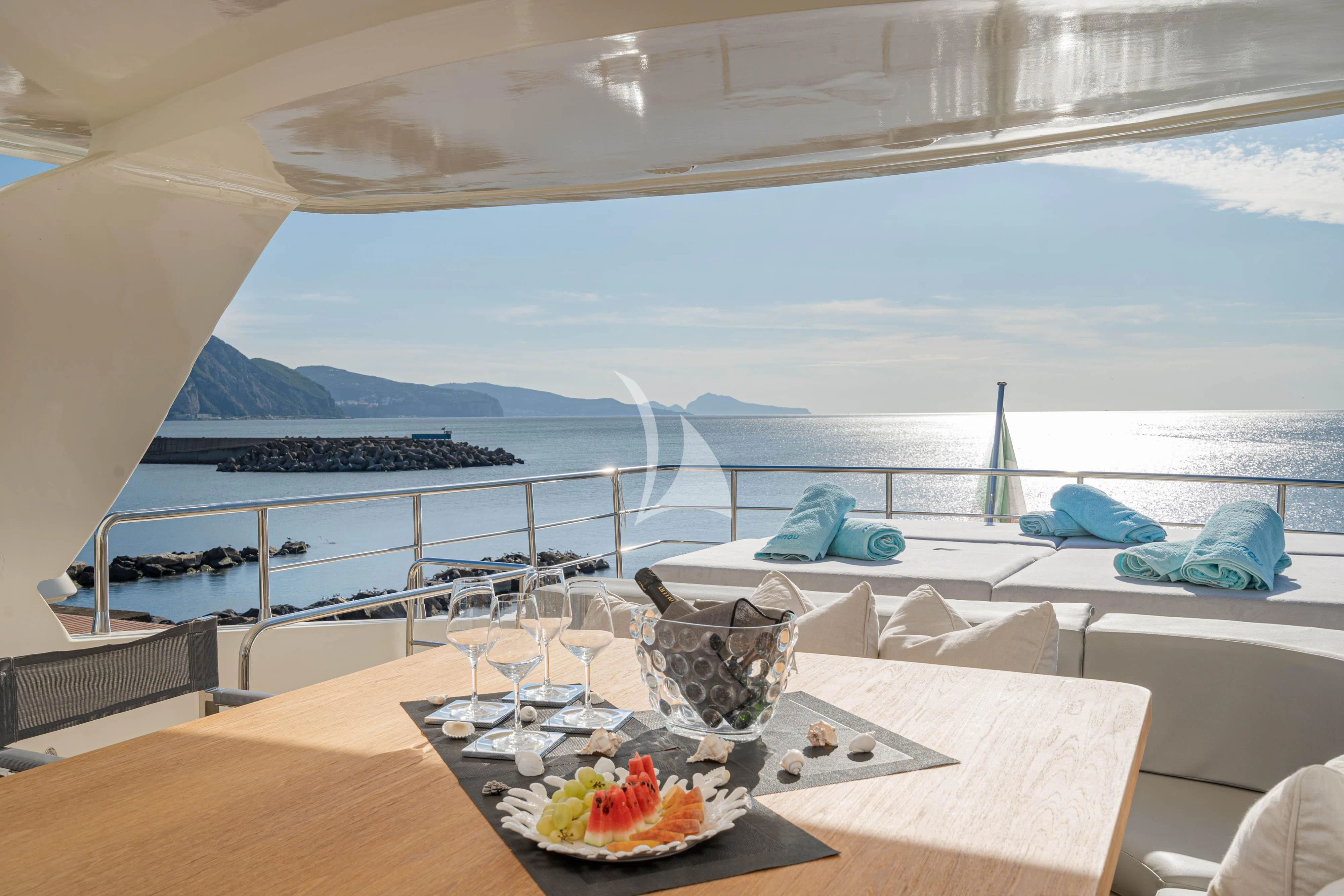 a table with food and drinks on it by a large body of water aboard MINOU Yacht for Sale
