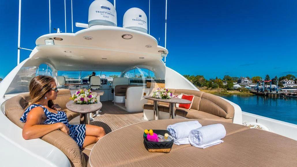 a woman sitting on a chair on a deck with a large white ship in the background aboard CEDAR ISLAND Yacht for Sale