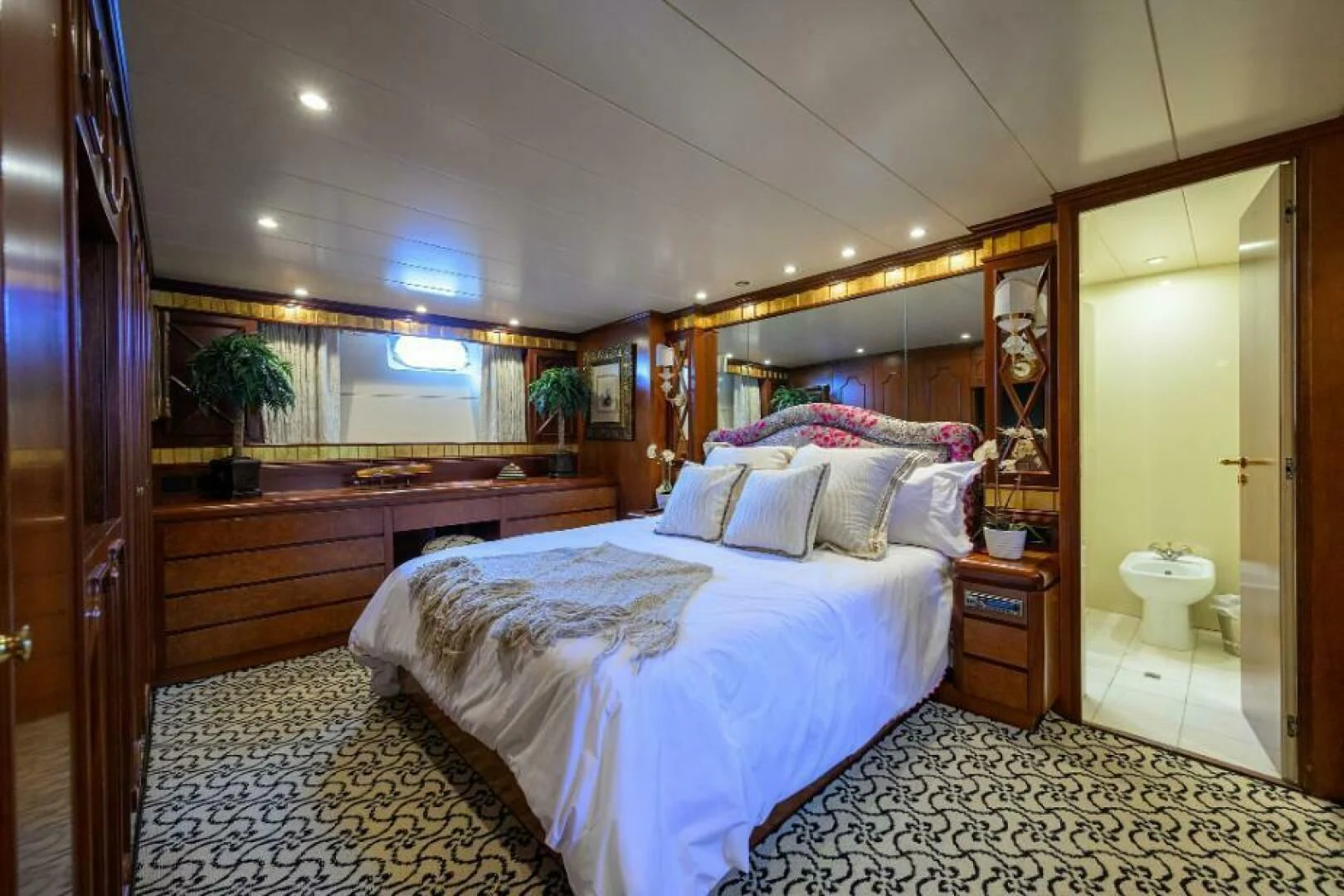 a bedroom with a bed and a mirror aboard CIPANGO Yacht for Sale