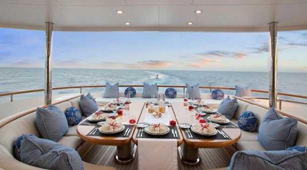 a table with plates and chairs on it next to a large body of water aboard HERCULES Yacht for Sale