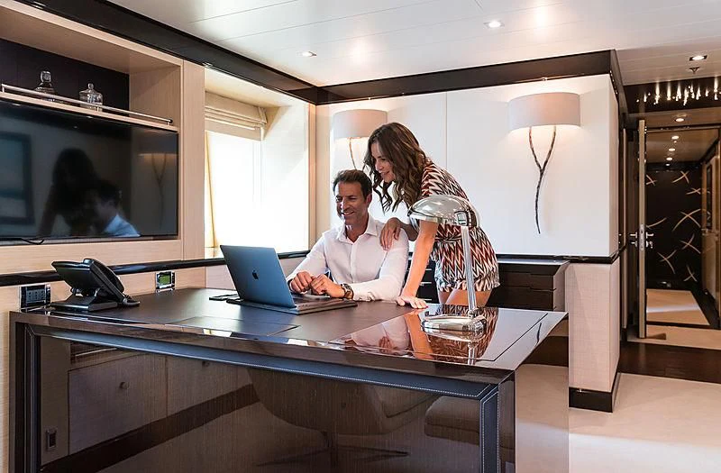 a man and a woman looking at a laptop aboard GRACE (YET) Yacht for Sale