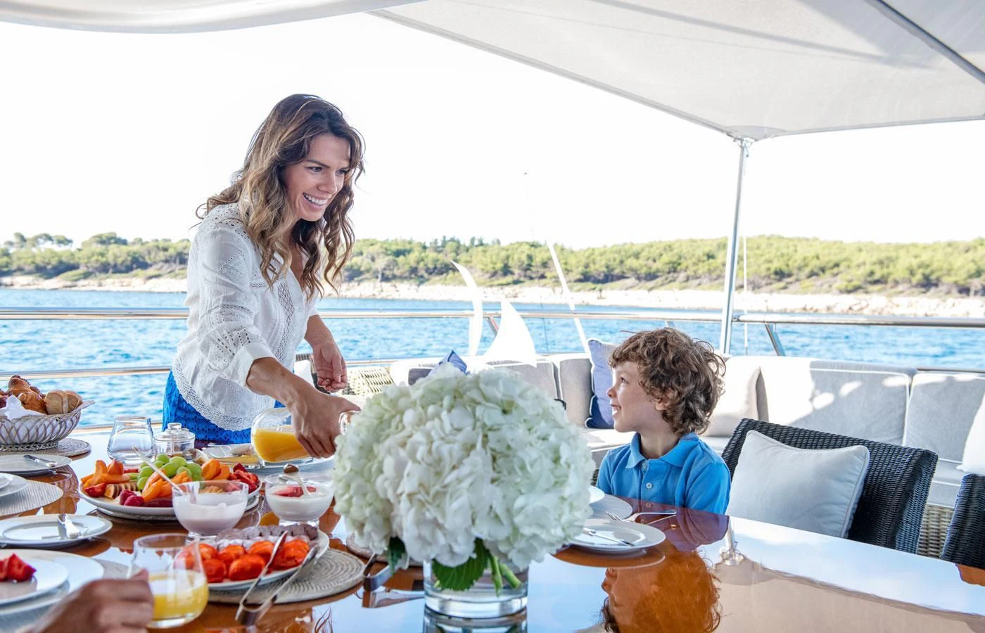 a woman and a boy sitting at a table with food and drinks aboard GRACE (YET) Yacht for Sale