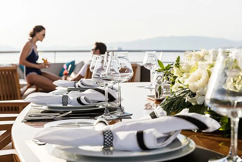 a group of people sitting at a table with wine glasses and flowers aboard GRACE (YET) Yacht for Sale