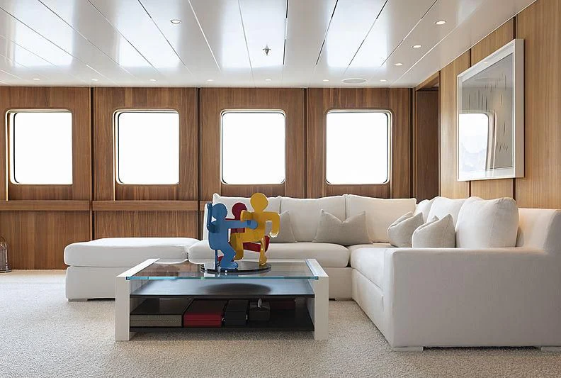 a living room with a white couch and a blue table aboard JESTER Yacht for Sale