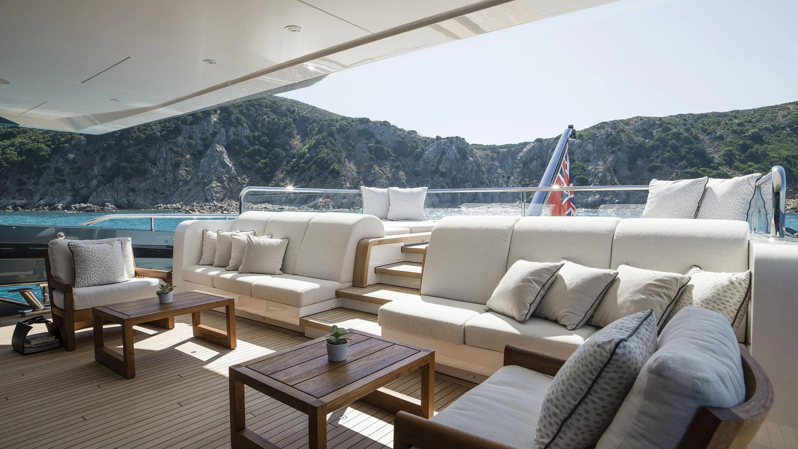 a living room with a large body of water and mountains in the background aboard IRISHA Yacht for Sale