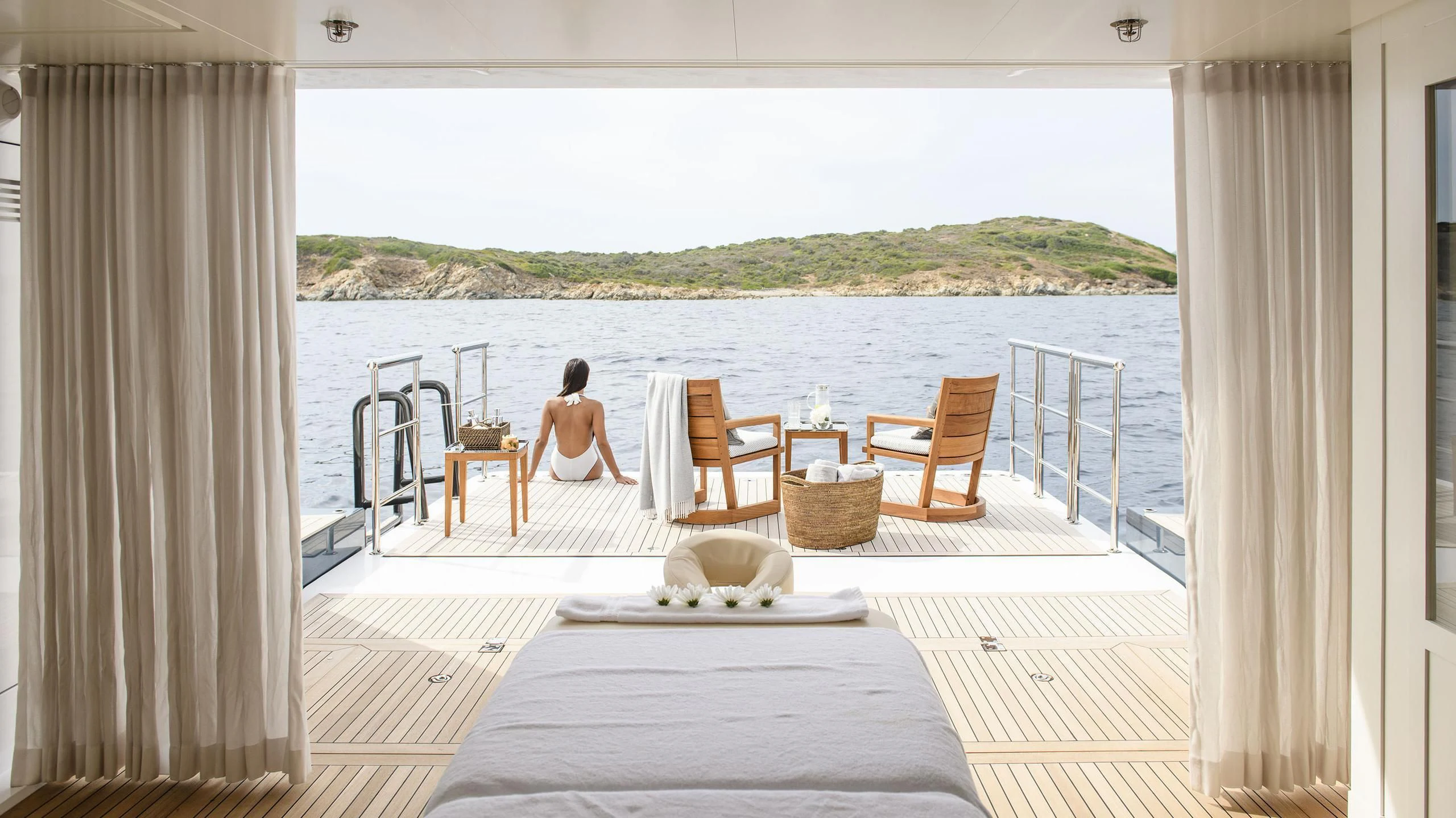a person sitting on a deck looking out to the water aboard IRISHA Yacht for Sale