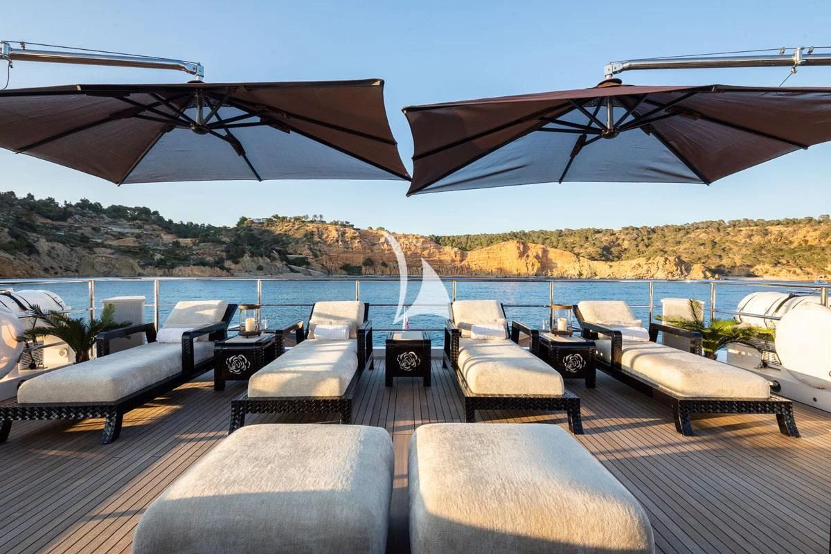 a deck with a large body of water and a large boat in the background aboard ILLUSION V Yacht for Charter