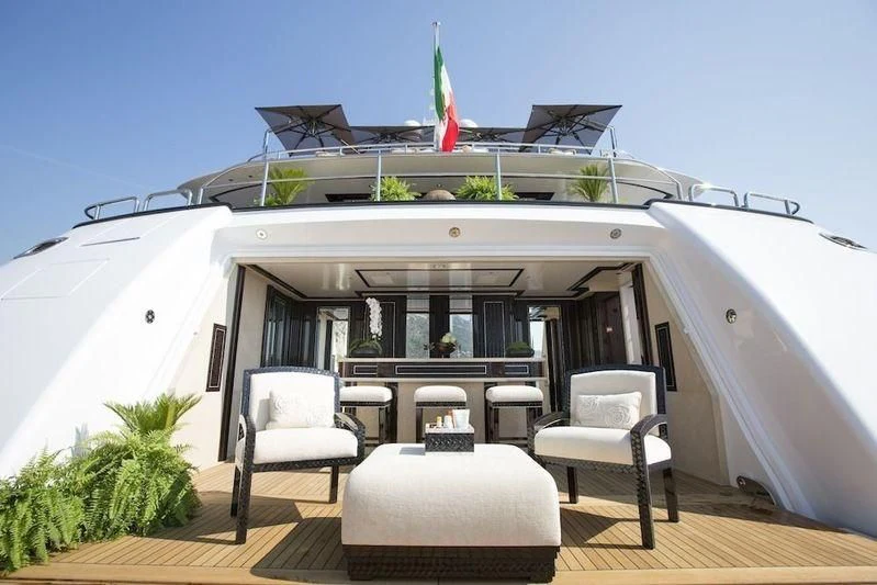 a large white boat with chairs and tables on a deck aboard ILLUSION V Yacht for Charter