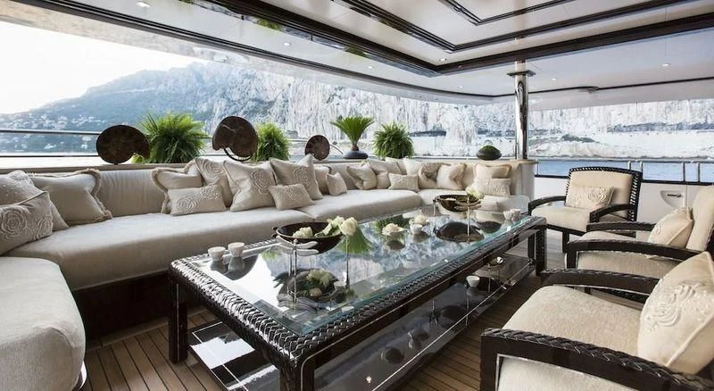 a living room with a large glass table and a large window aboard ILLUSION V Yacht for Charter