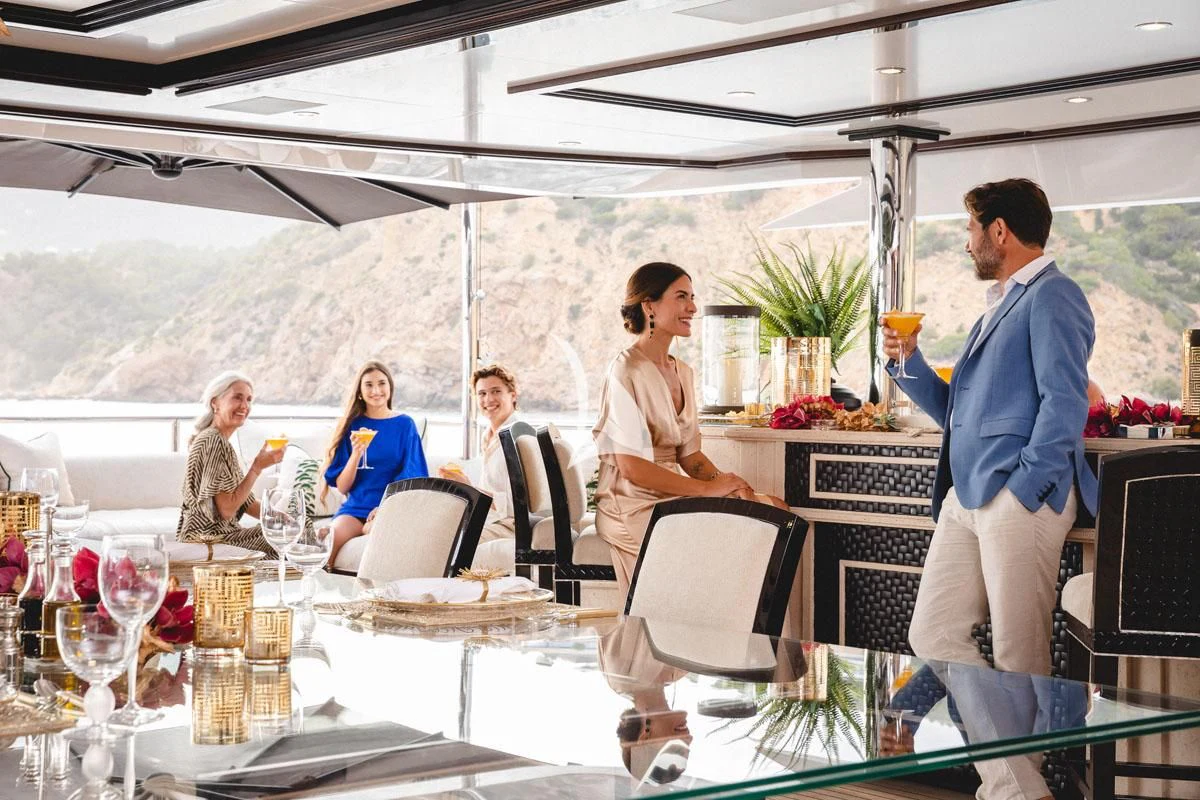 a group of people sitting at a table with wine glasses and drinks aboard ILLUSION V Yacht for Charter