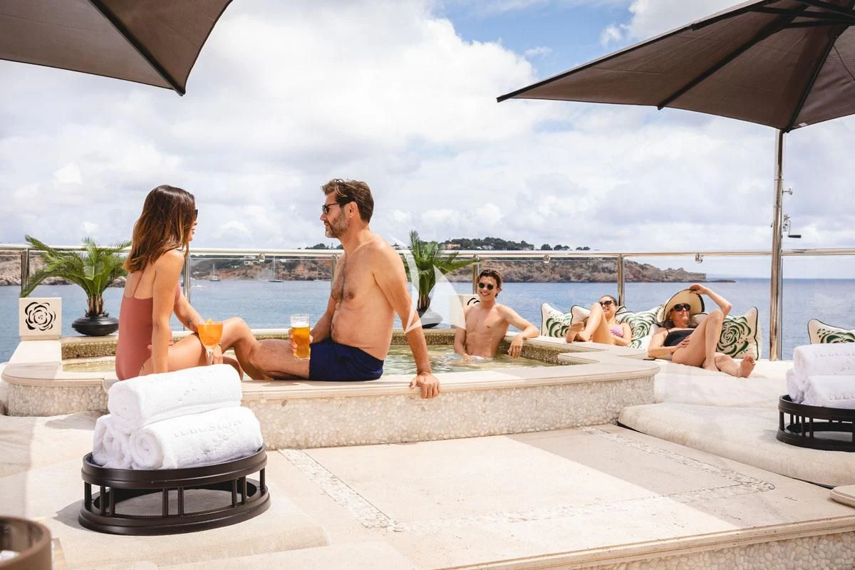 a group of people sitting on a beach with a cake and a drink aboard ILLUSION V Yacht for Charter