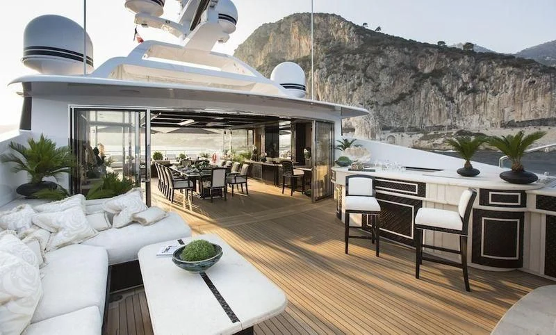 a room with a table chairs and a large building with a mountain in the background aboard ILLUSION V Yacht for Charter