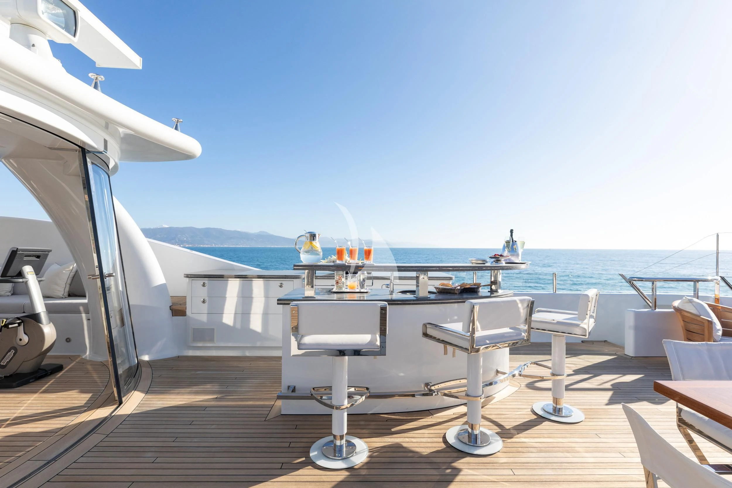 a deck with chairs and tables on it by the water aboard REVELRY Yacht for Sale