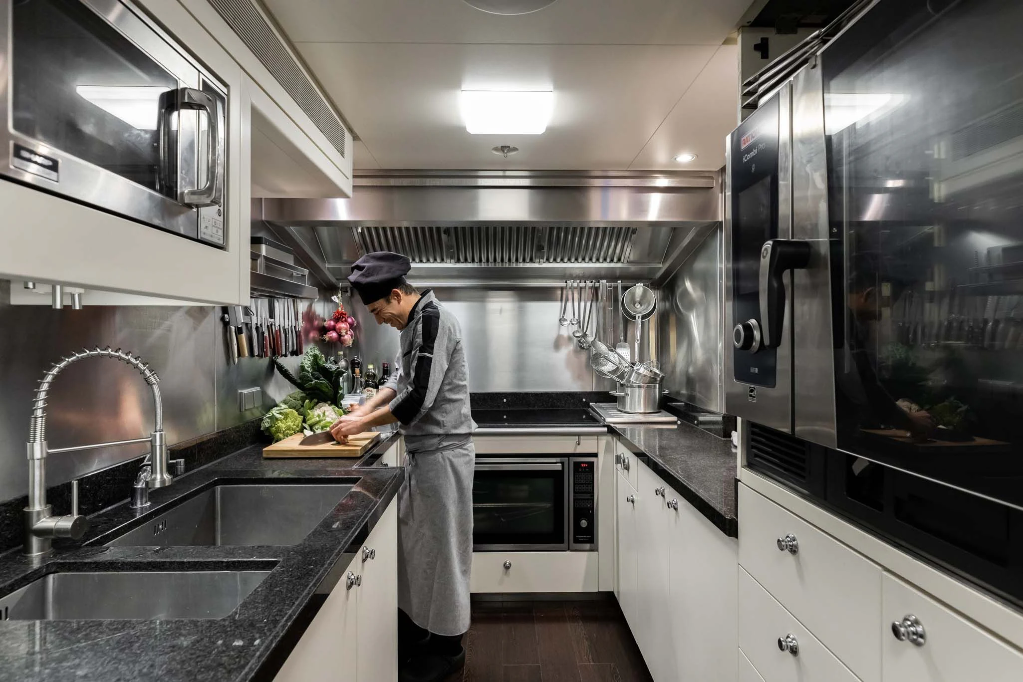a person in a kitchen preparing food aboard REVELRY Yacht for Sale