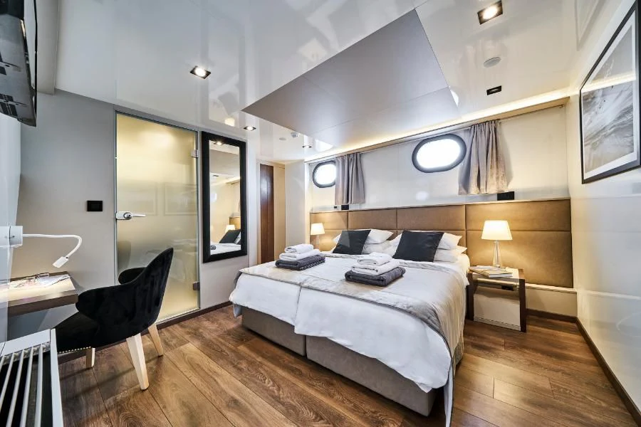 a bedroom with a bed and a desk aboard RARA AVIS Yacht for Charter