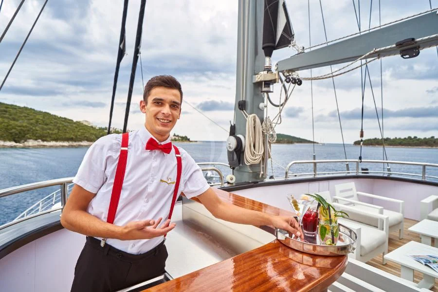 a man holding a drink on a boat aboard RARA AVIS Yacht for Charter