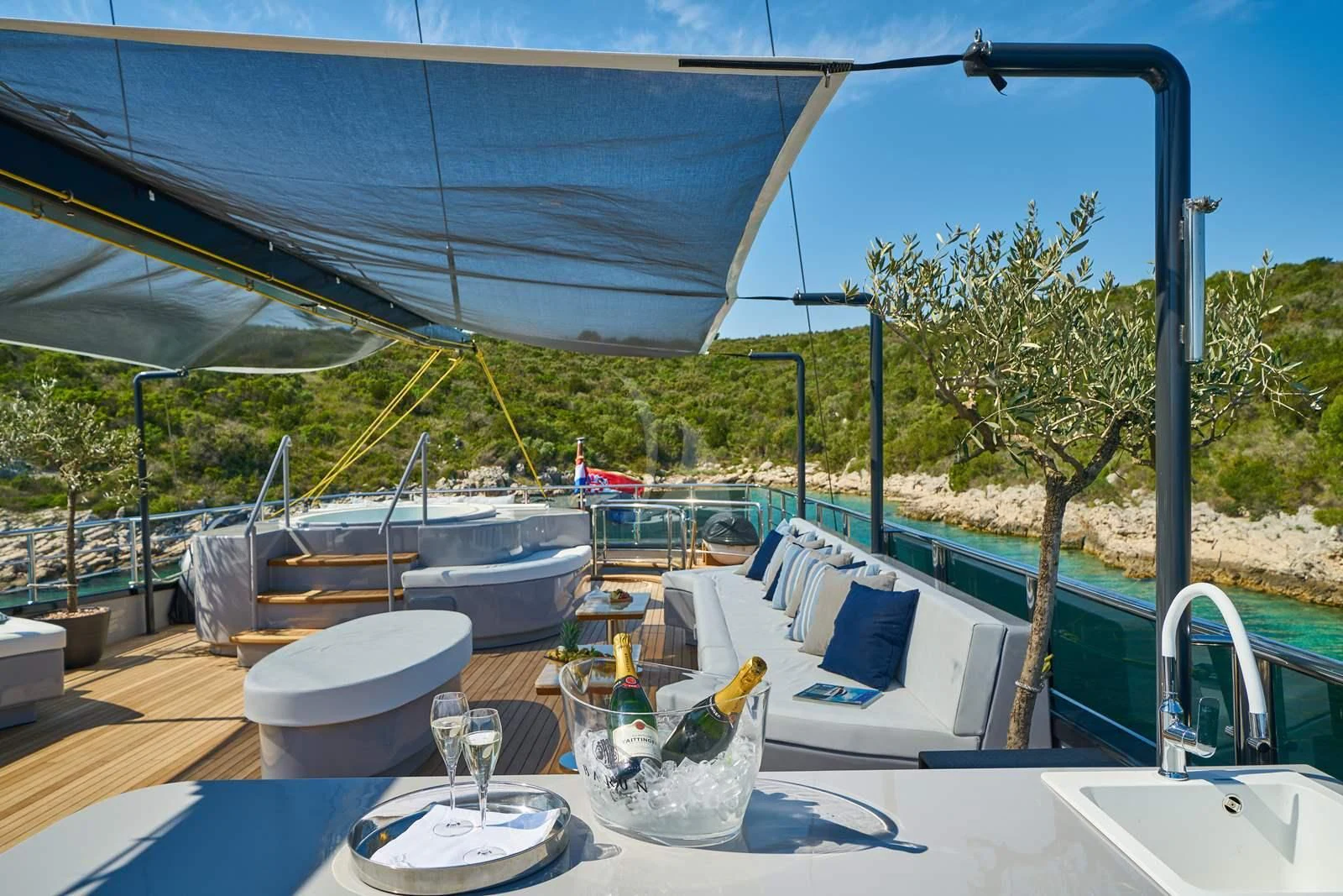 a table with chairs and a table with a glass and a view of a lake and trees and aboard RARA AVIS Yacht for Charter