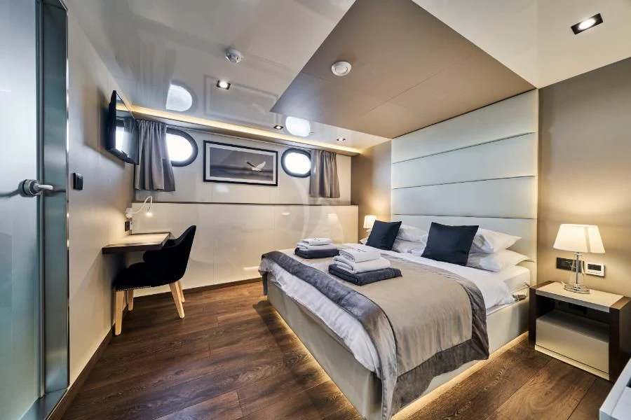 a bedroom with a bed and a chair aboard RARA AVIS Yacht for Charter