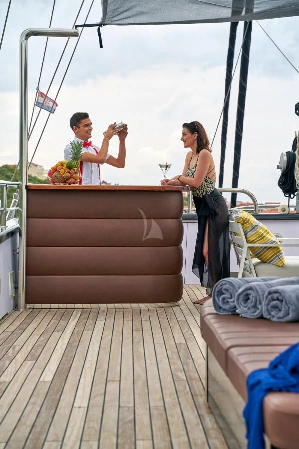 a man and woman standing on a boat and holding a glass of wine aboard RARA AVIS Yacht for Charter