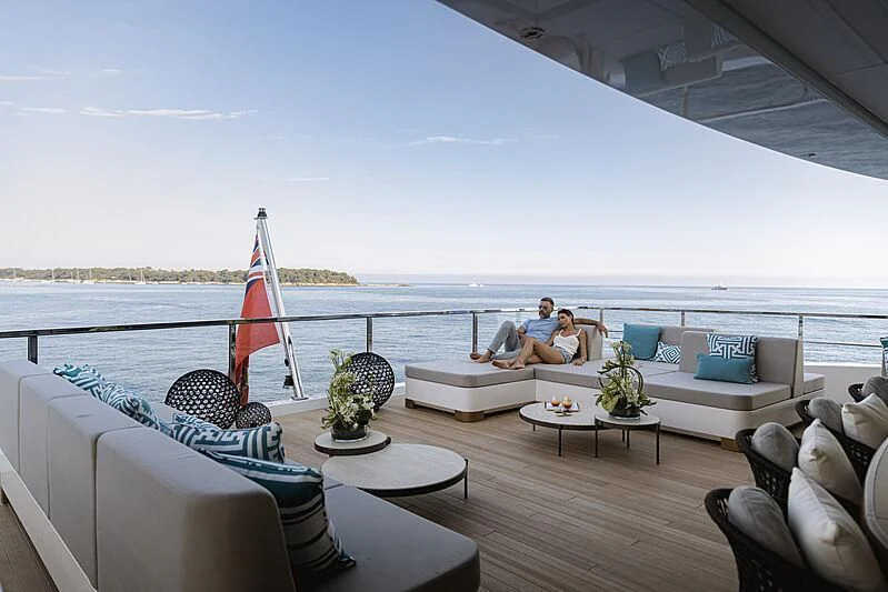 a couple sitting on a couch on a deck overlooking the ocean aboard LEMON TREE Yacht for Charter