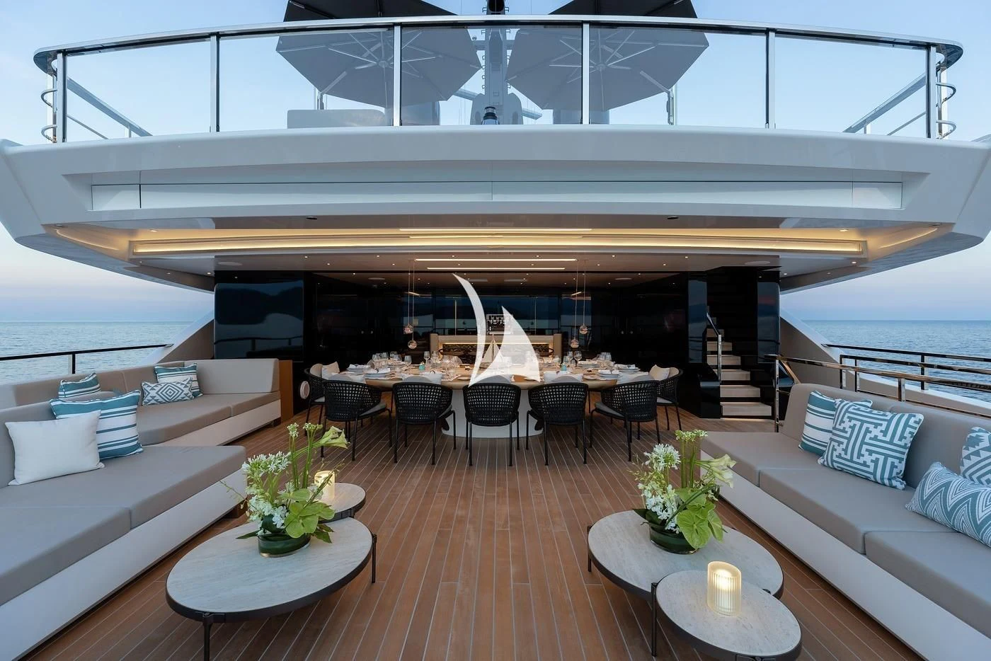 a room with a wood floor and a large white lounge chair and a table with a plant on aboard LEMON TREE Yacht for Charter