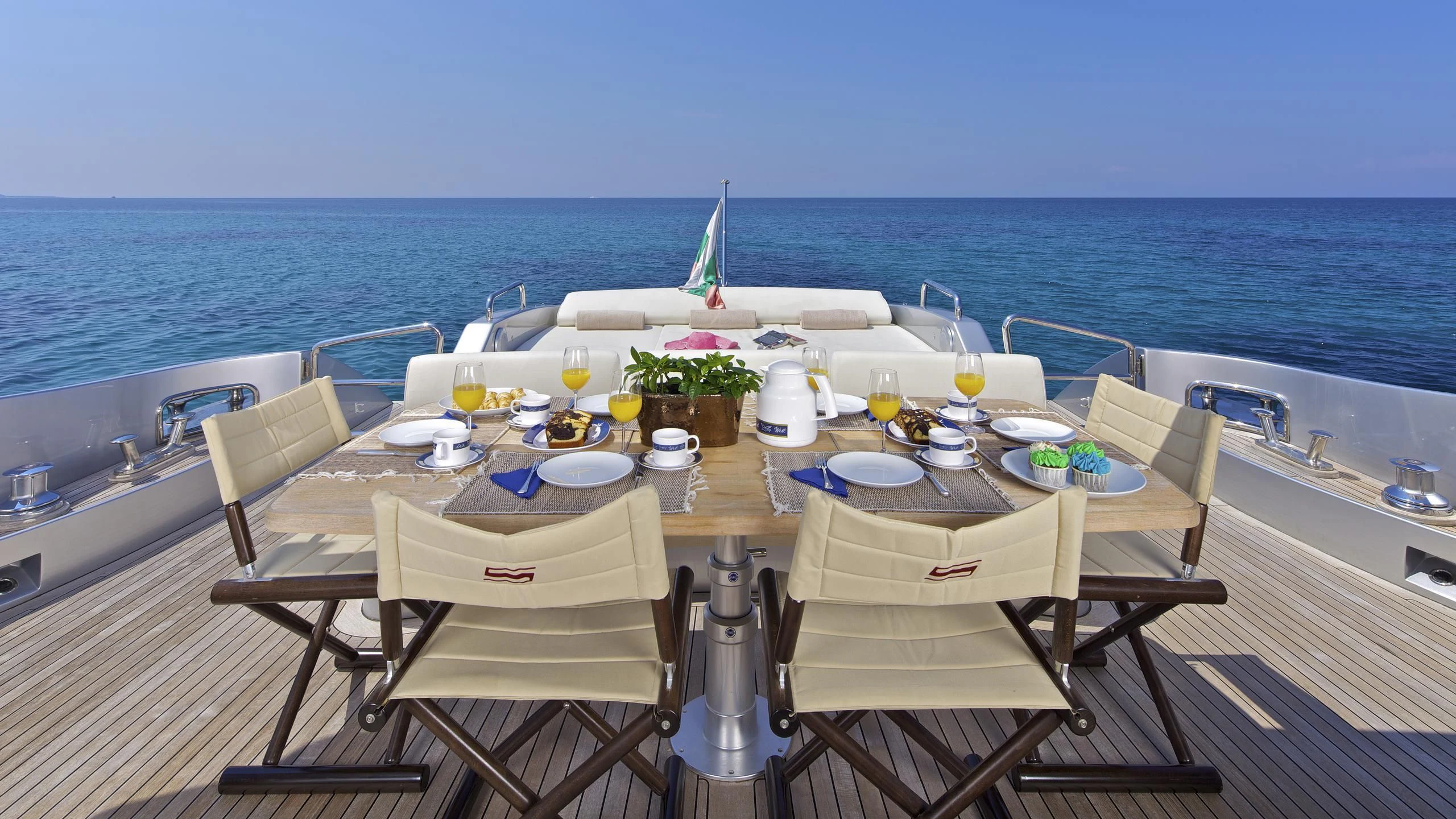 a table with chairs on it next to a body of water aboard THEA MALTA Yacht for Sale