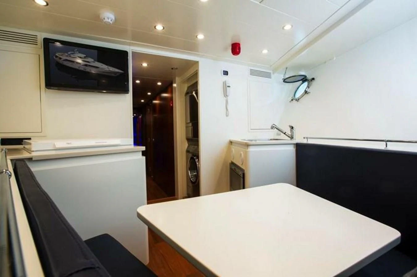 a kitchen with a table and a tv on the wall aboard M.C. Yacht for Sale