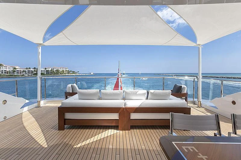 a lounge area with a large blue umbrella over a body of water aboard E.MOTION+ Yacht for Sale