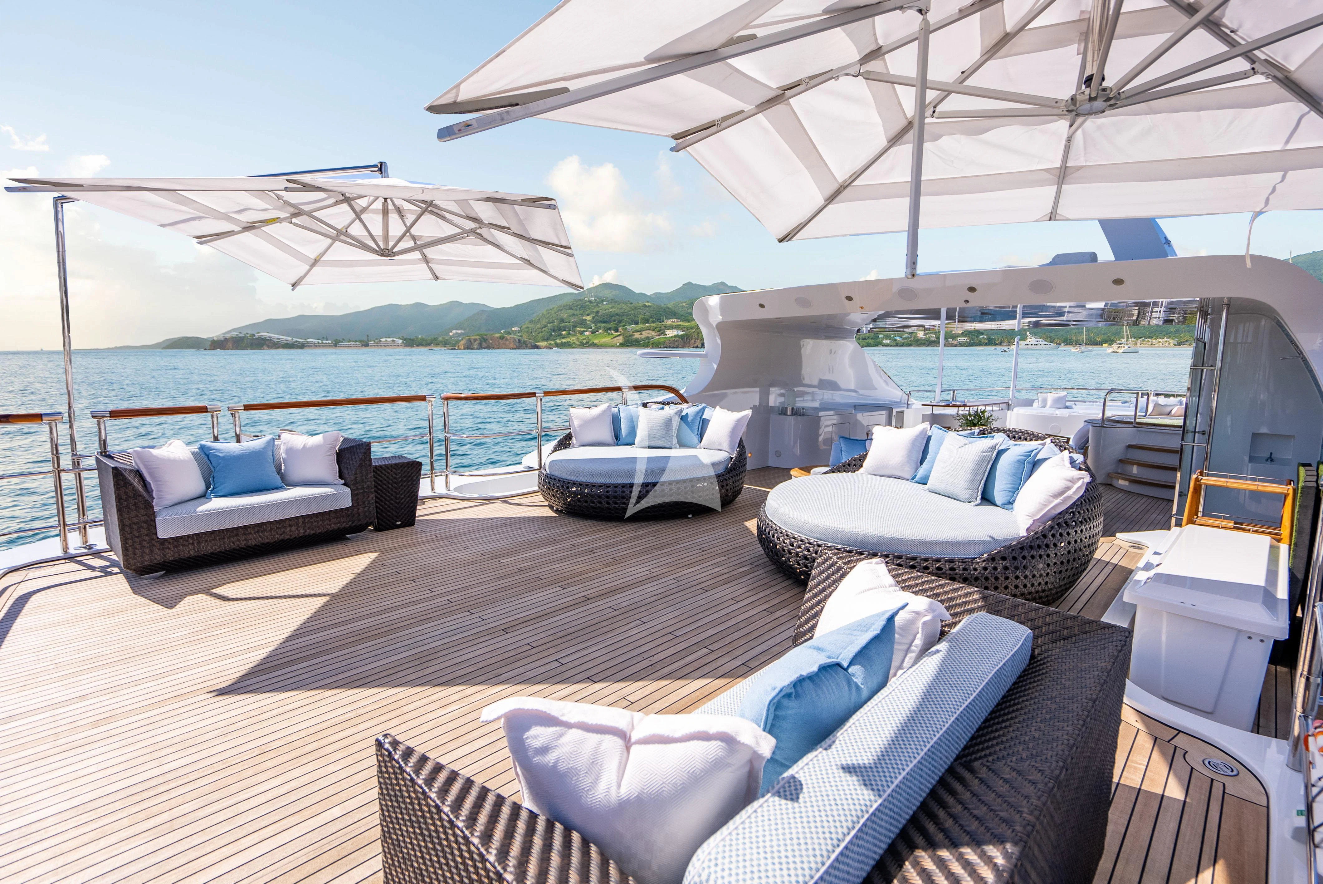 a large lounge area with a large body of water and a large building in the background aboard LADY BRAVE Yacht for Sale
