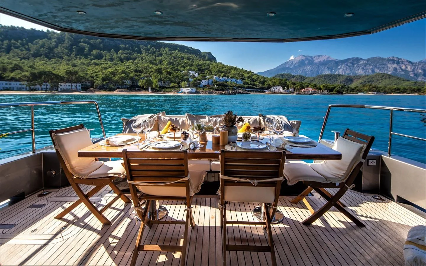 a table set for a meal on a deck overlooking a large body of water aboard BERING B82 Yacht for Sale